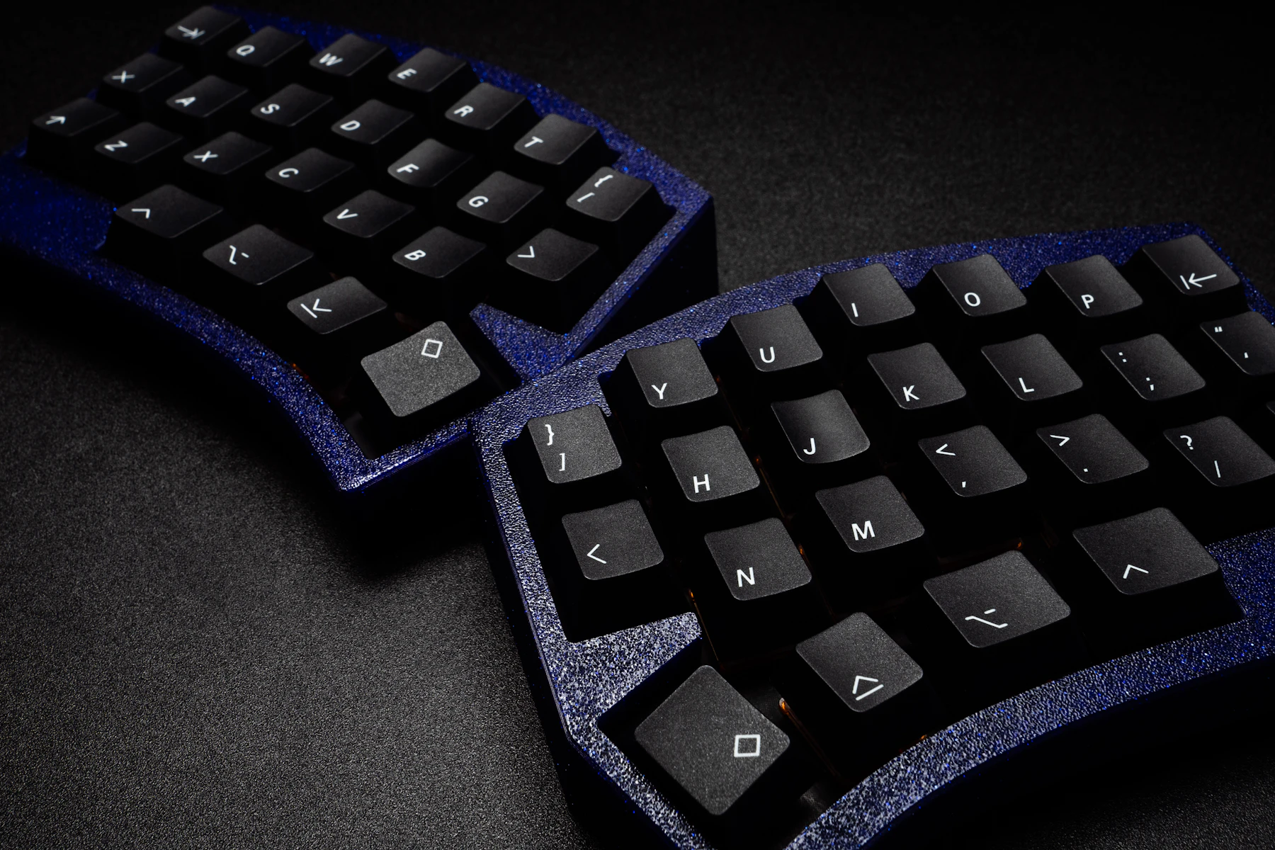 Close-up of a black split ergonomic keyboard on a dark surface