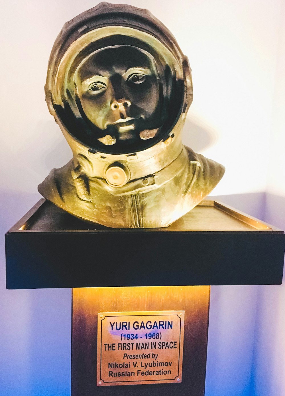 gold human head bust on white wooden shelf