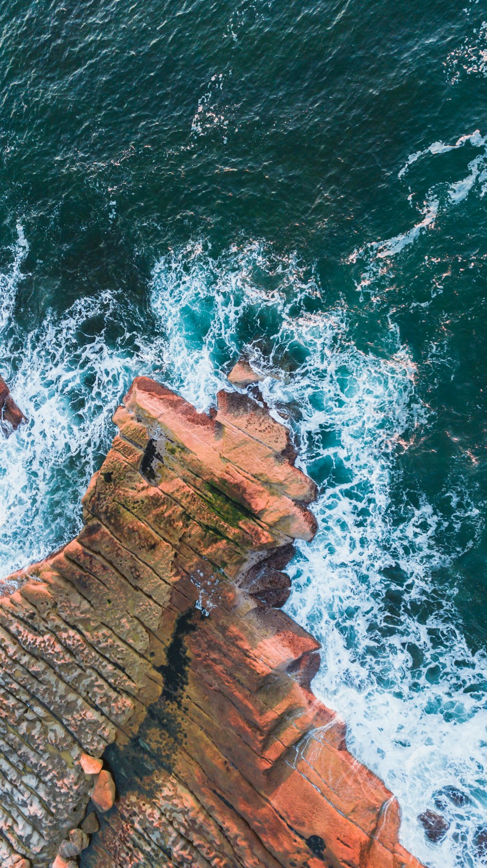 brown rock formation on body of water during daytime