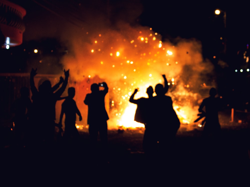 silhueta de pessoas em pé no campo com fogos de artifício