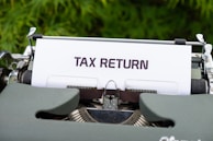 a close up of a typewriter with a tax return sign on it
