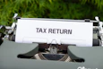 a close up of a typewriter with a tax return sign on it