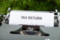 a close up of a typewriter with a tax return sign on it