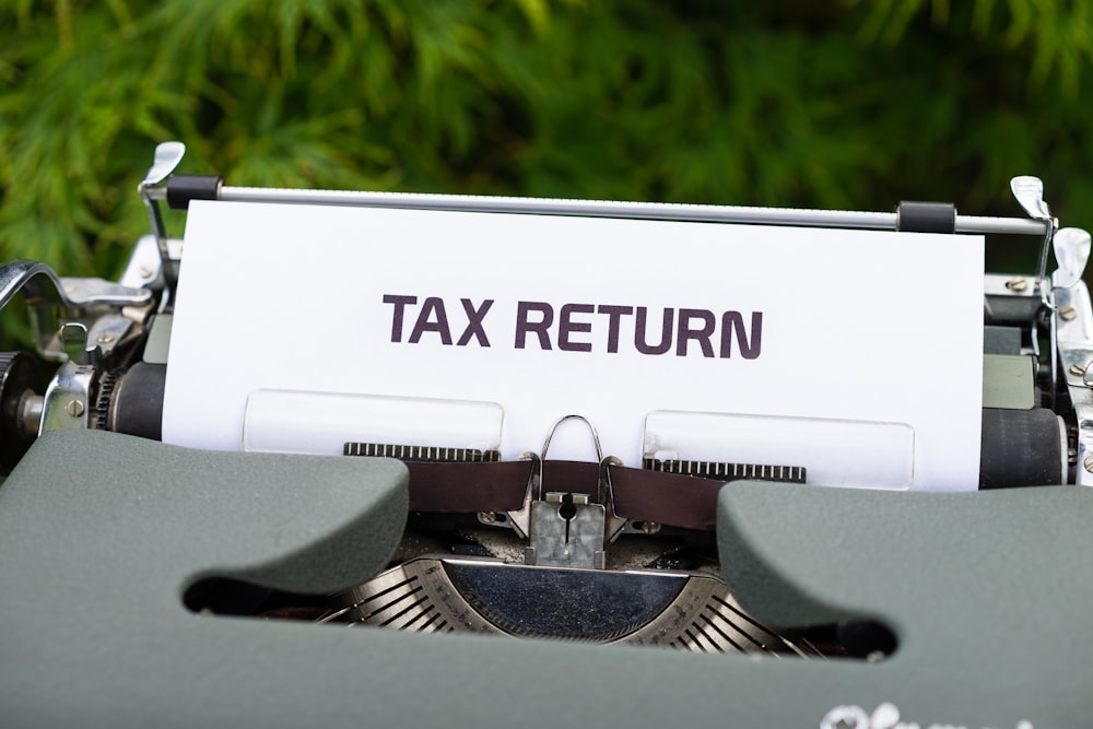 a close up of a typewriter with a tax return sign on it