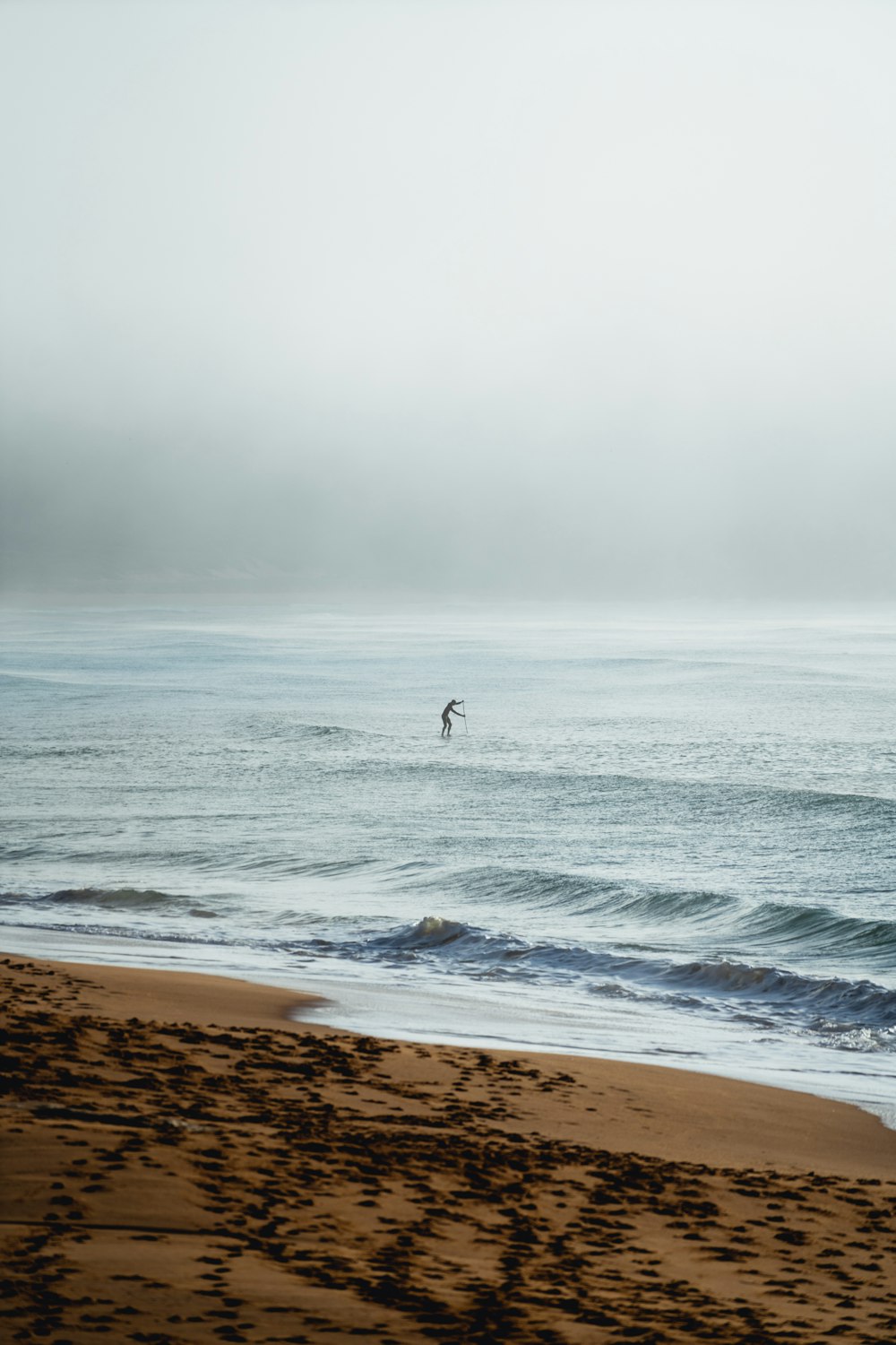 person in black wet suit walking on seashore during daytime