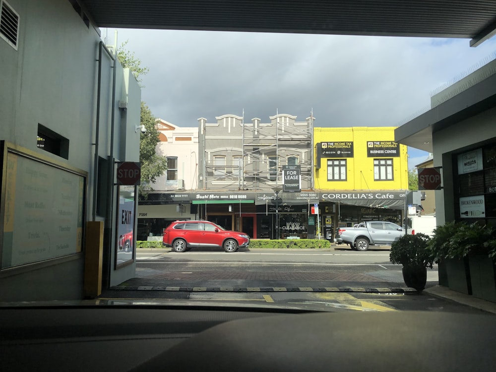 red car parked in front of yellow building