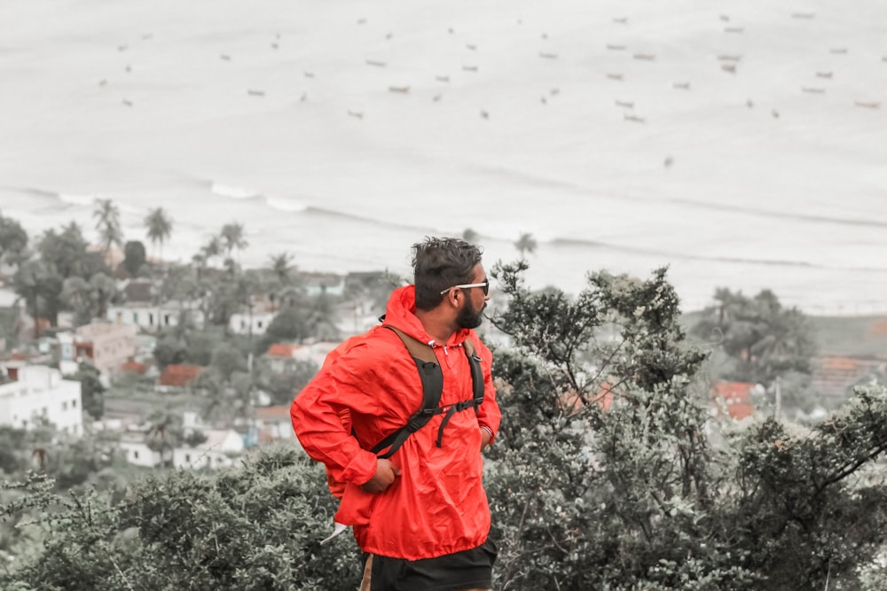 man in red jacket standing on snow covered ground during daytime