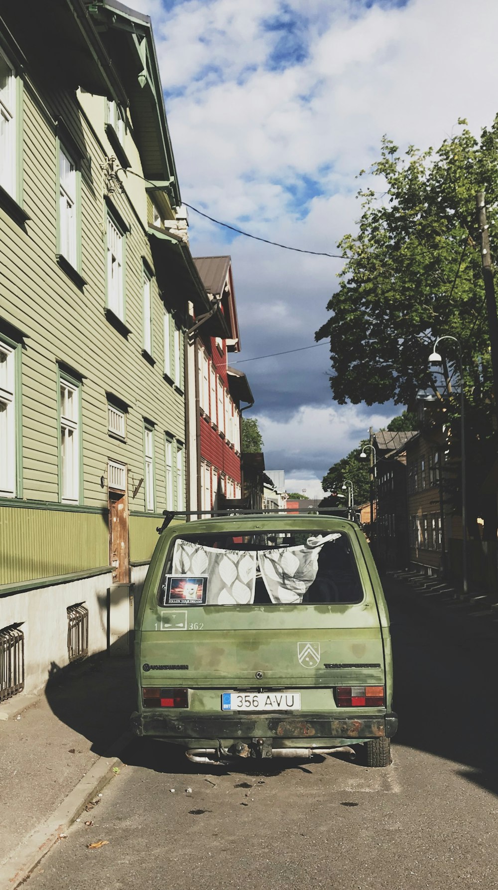 green car parked beside red and white concrete building during daytime