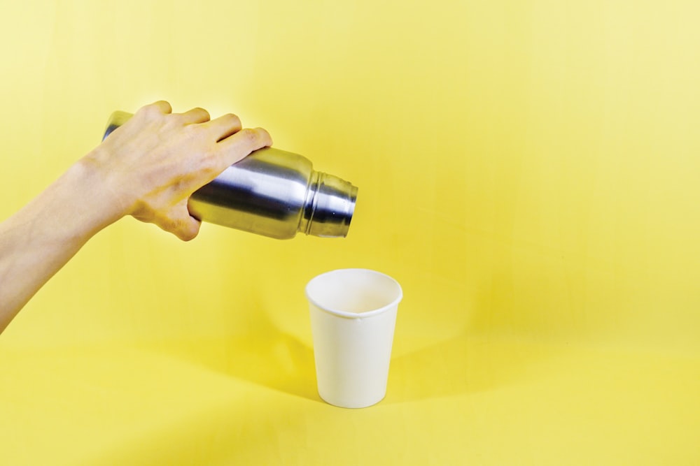 person pouring white liquid on white cup