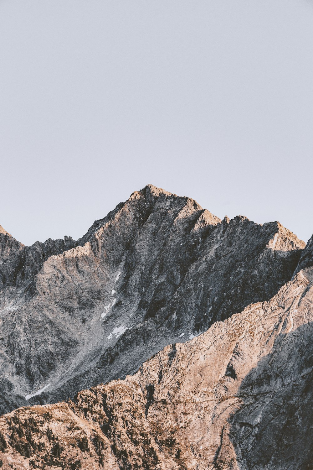 montanha rochosa marrom sob o céu branco durante o dia