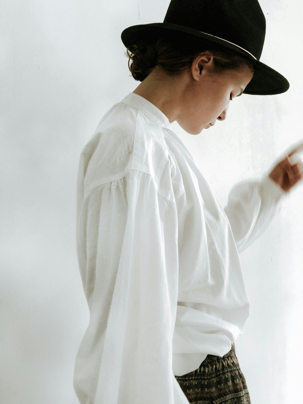 woman in white dress shirt and black fedora hat