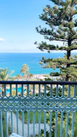 Balcony view overlooking turquoise waters and swaying palm trees at a boutique hotel.