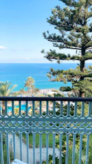 Balcony view overlooking turquoise waters and swaying palm trees at a boutique hotel.