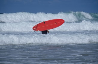 red surfboard on sea waves during daytime