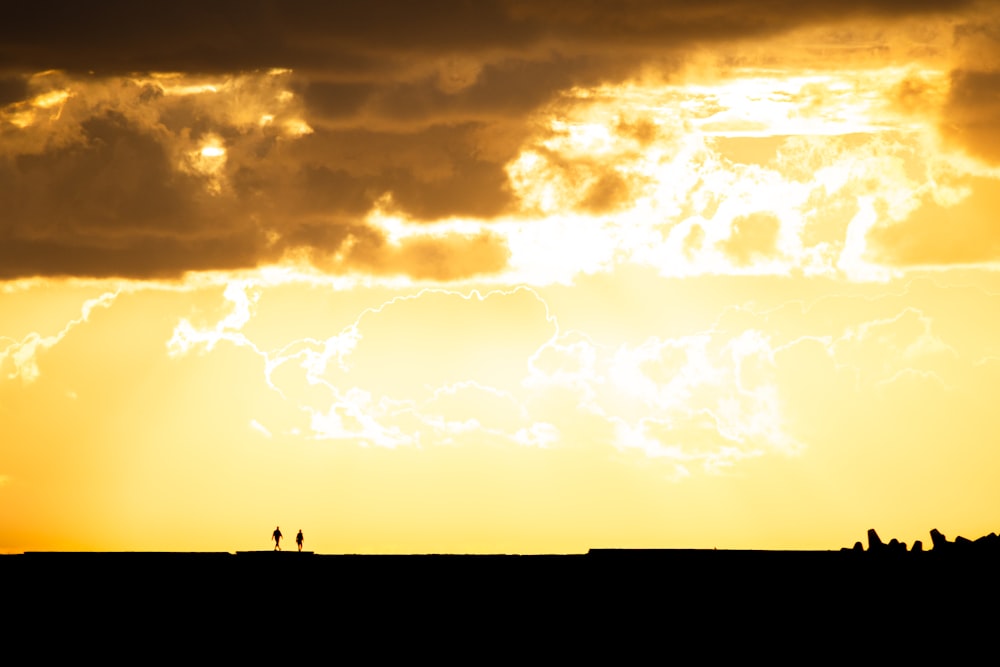 silhouette of person standing on the seashore during sunset