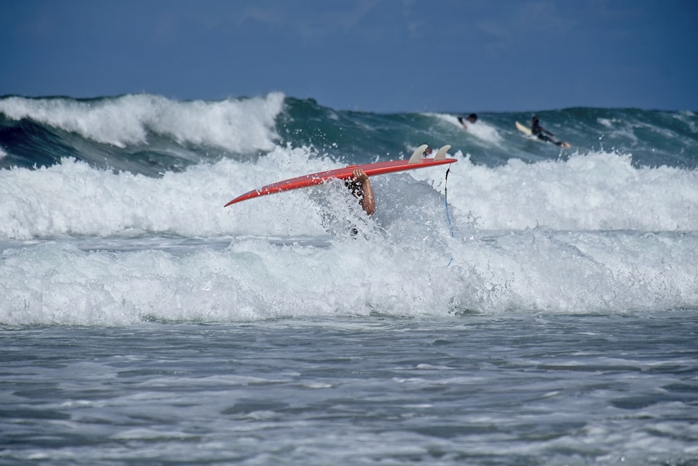 prancha de surf vermelha nas ondas do mar durante o dia