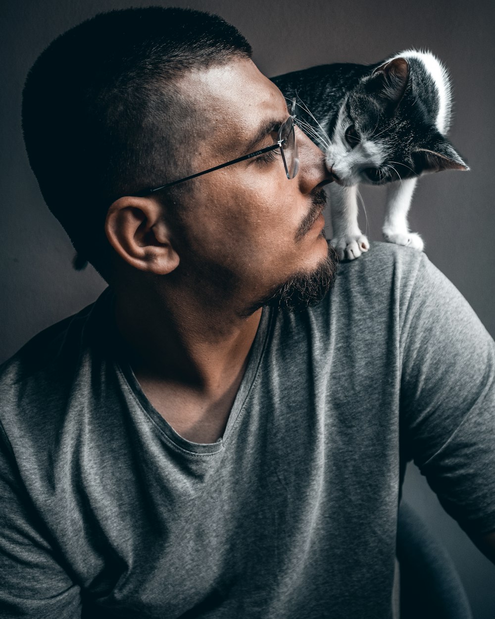 man in gray crew neck shirt holding white and black cat