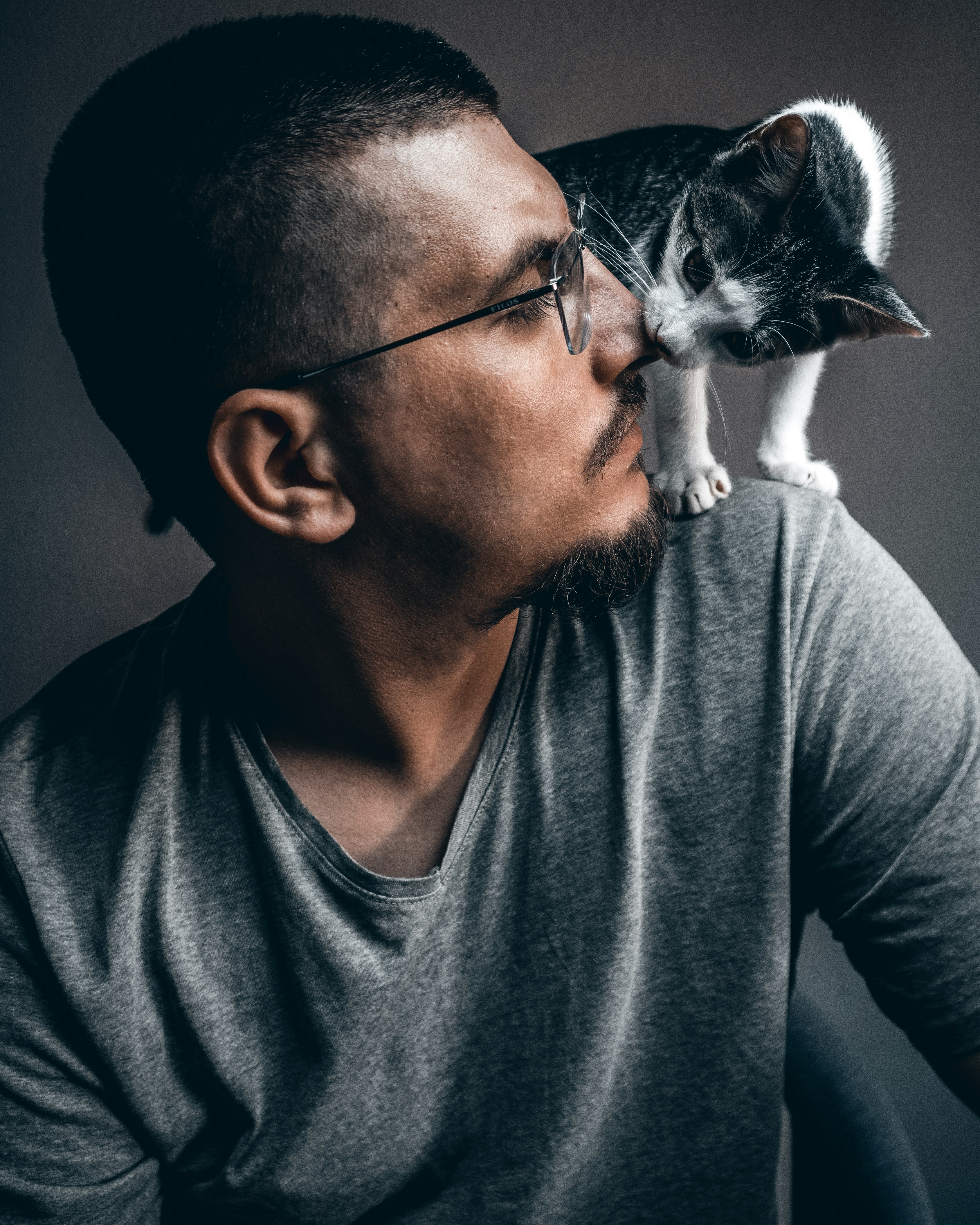 man in gray crew neck shirt holding white and black cat
