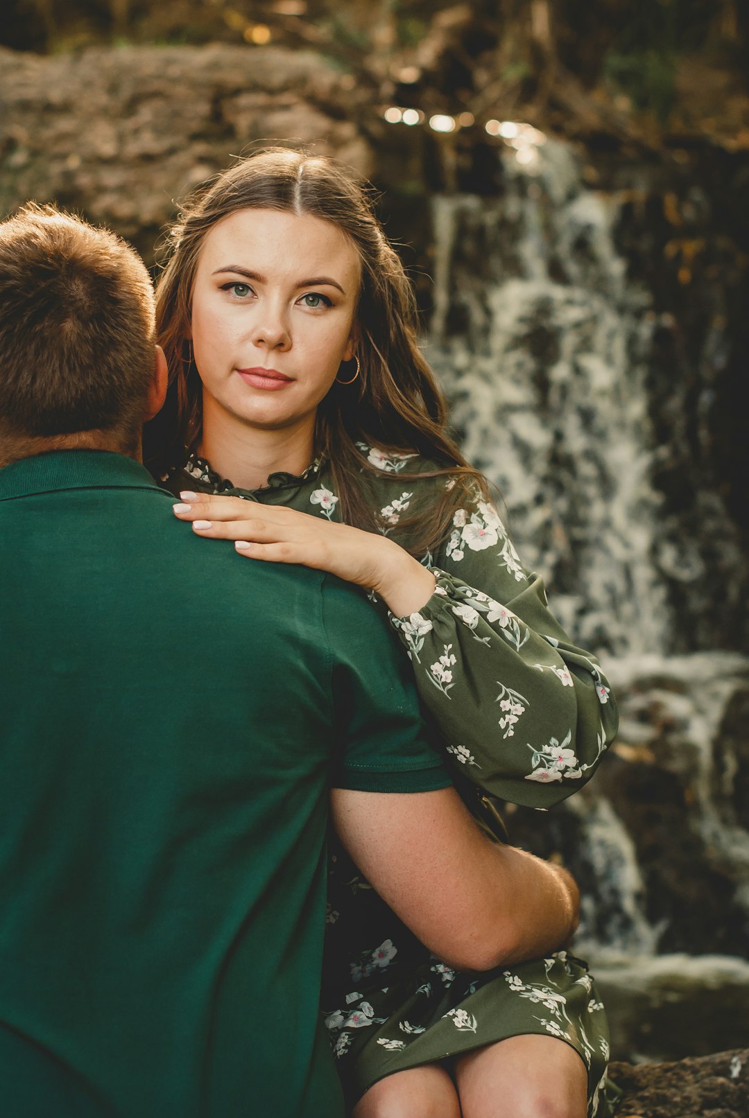 woman in green and brown floral dress hugging man in green t-shirt