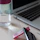 Close-up of a pastel pink stainless steel bottle on a wooden desk next to notebooks and a laptop.