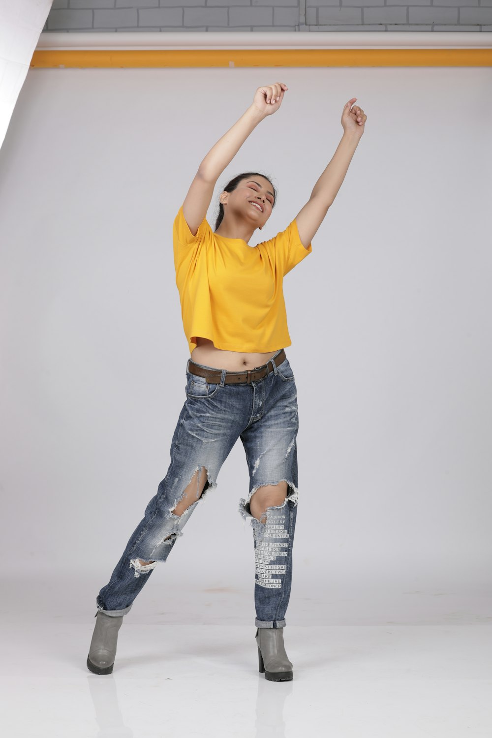 man in yellow crew neck t-shirt and blue denim jeans raising his hands