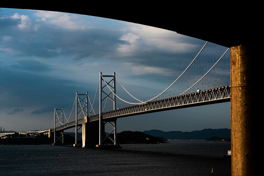 bridge over body of water under cloudy sky during daytime