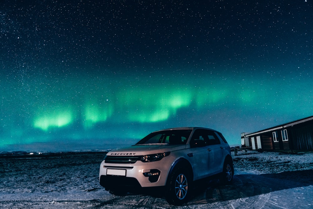 white suv on snow covered ground during night time