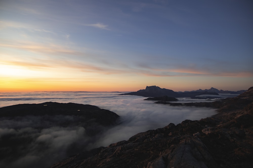 Montaña rocosa negra cerca del cuerpo de agua durante la puesta del sol