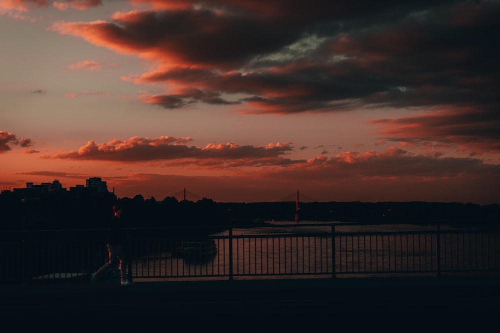 silhouette of people standing on bridge during sunset