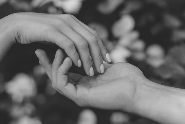 Close-up of two hands gently touching, set against a sleek black and gold background.