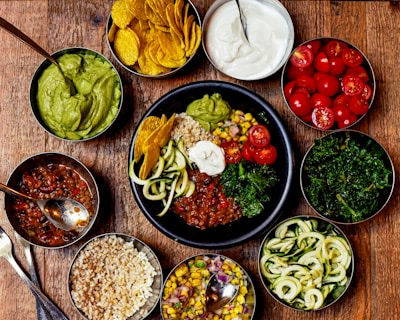 Colorful bowls of homemade salsas and side dishes on a rustic wooden table.