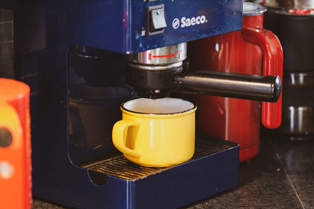 yellow ceramic mug on black and red coffee maker