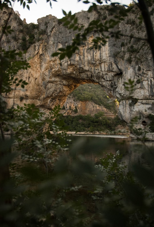 gray rocky mountain beside body of water during daytime in Ardèche France