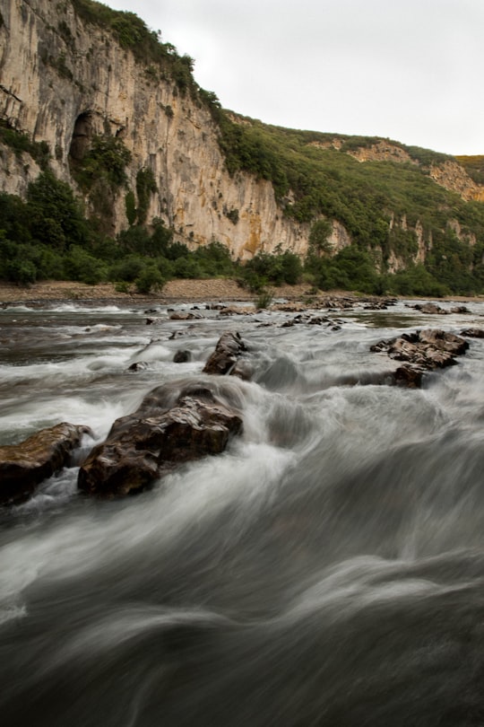 brown rocky mountain beside river during daytime in Ardèche France