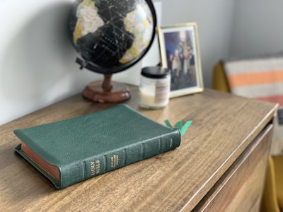 green hardbound book on brown wooden table