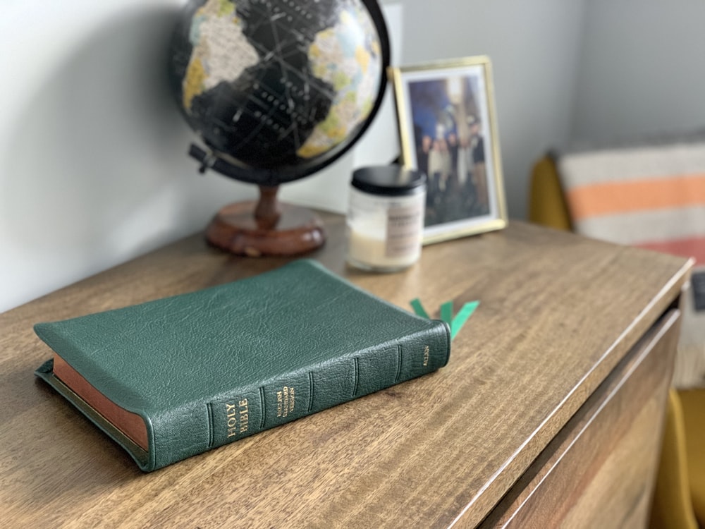 green hardbound book on brown wooden table