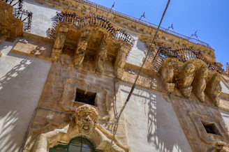 Historic colonial building facade in Puebla with intricate stonework and wooden balconies under a clear blue sky.