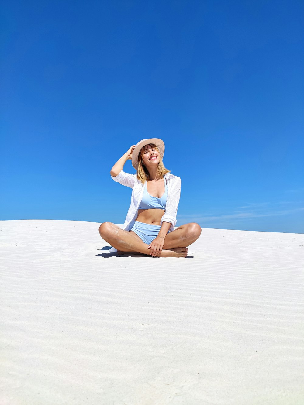 woman in white dress sitting on sand during daytime