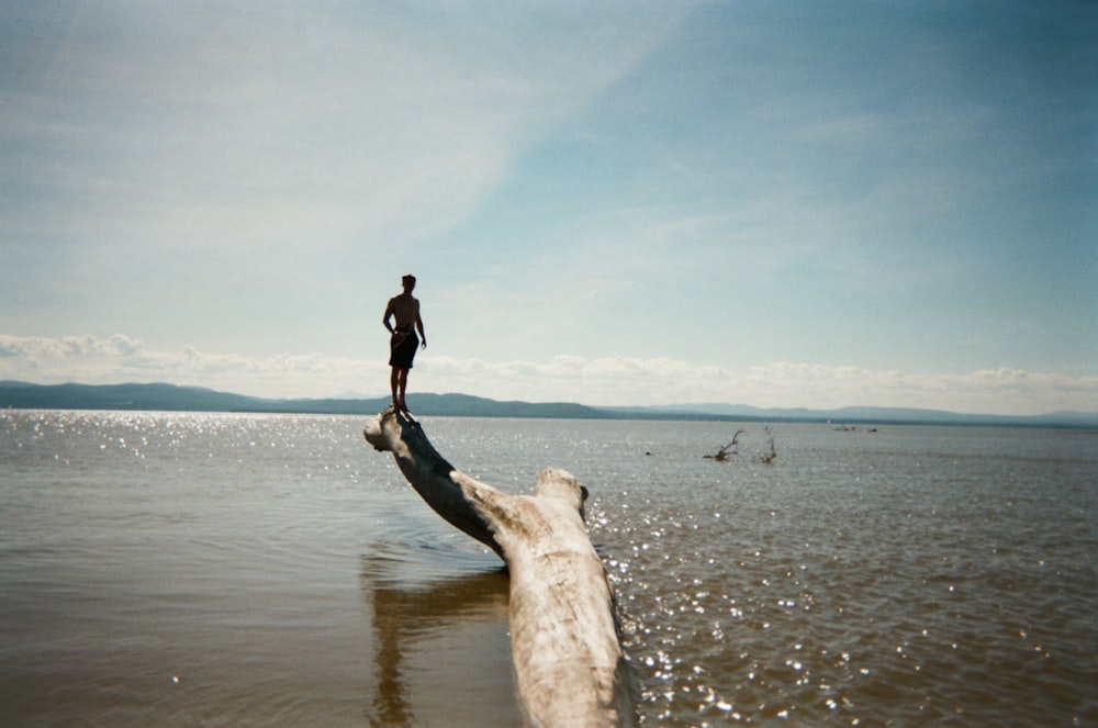 woman in black jacket and black pants standing on brown sand near sea during daytime