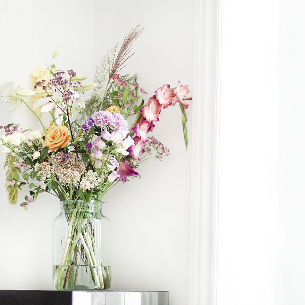 fleurs roses et jaunes dans un vase en verre transparent