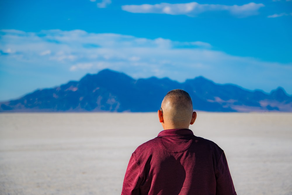 man in red long sleeve shirt standing on beach during daytime