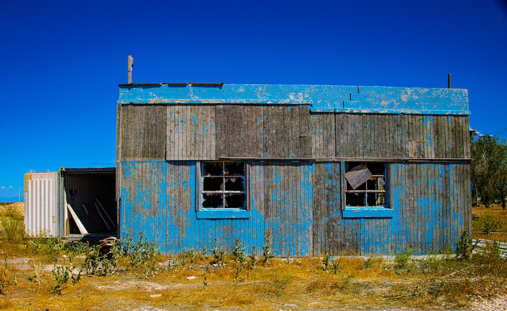 Casa de madera azul en campo de hierba verde durante el día