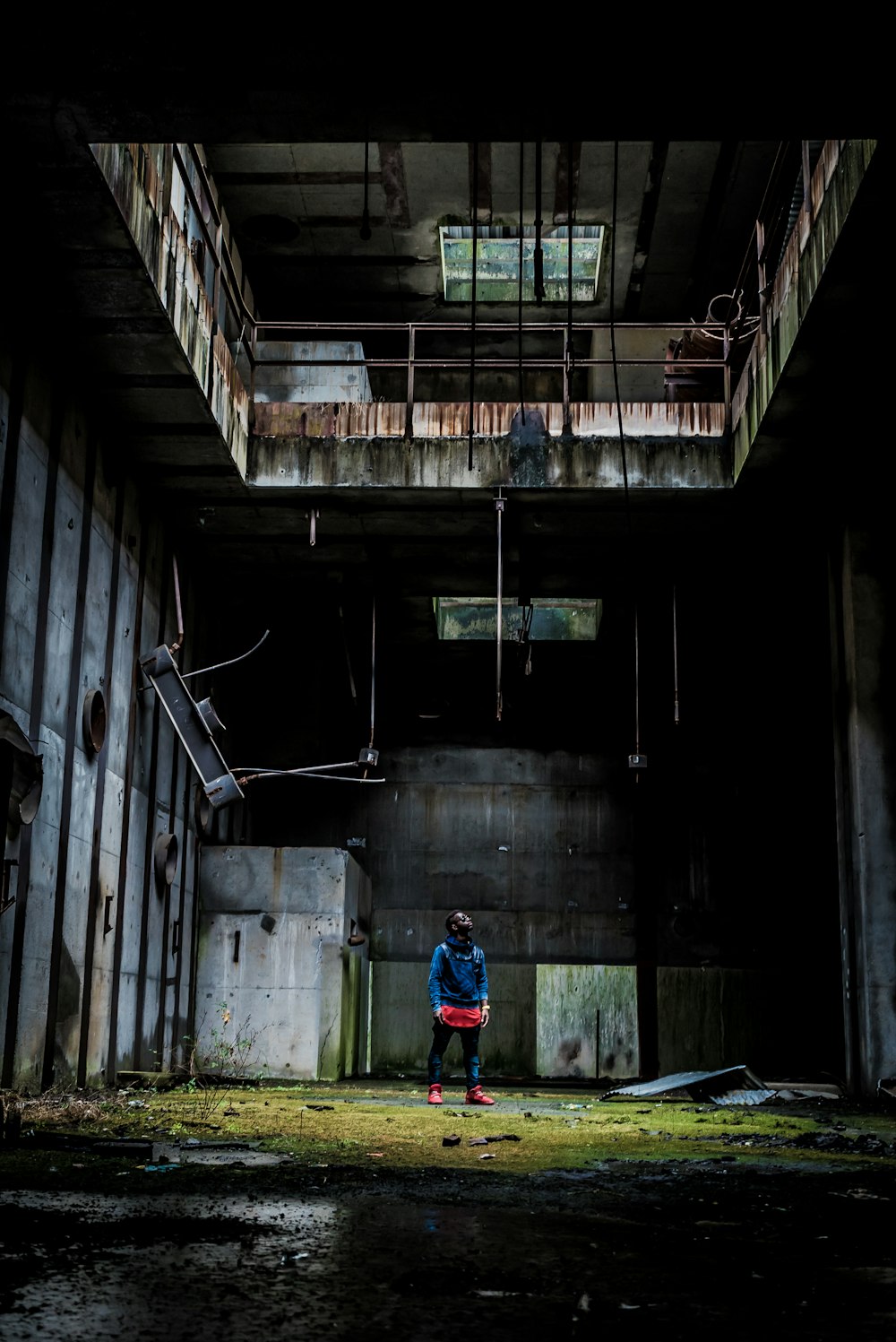 man in blue jacket and blue denim jeans standing on abandoned building