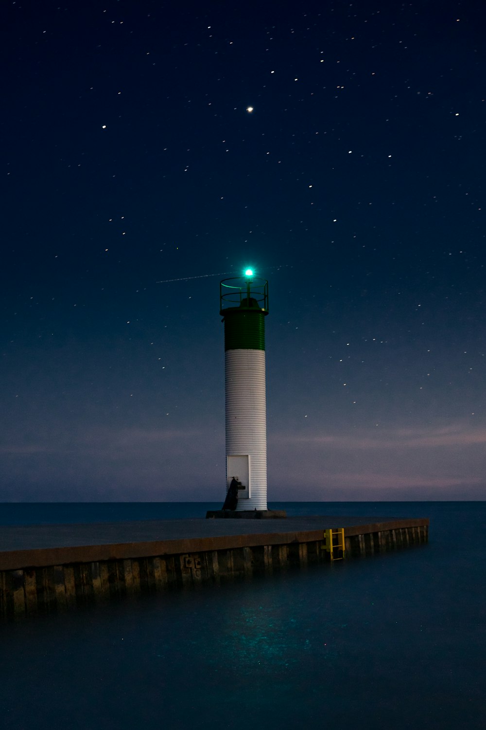 white and black lighthouse near body of water during night time