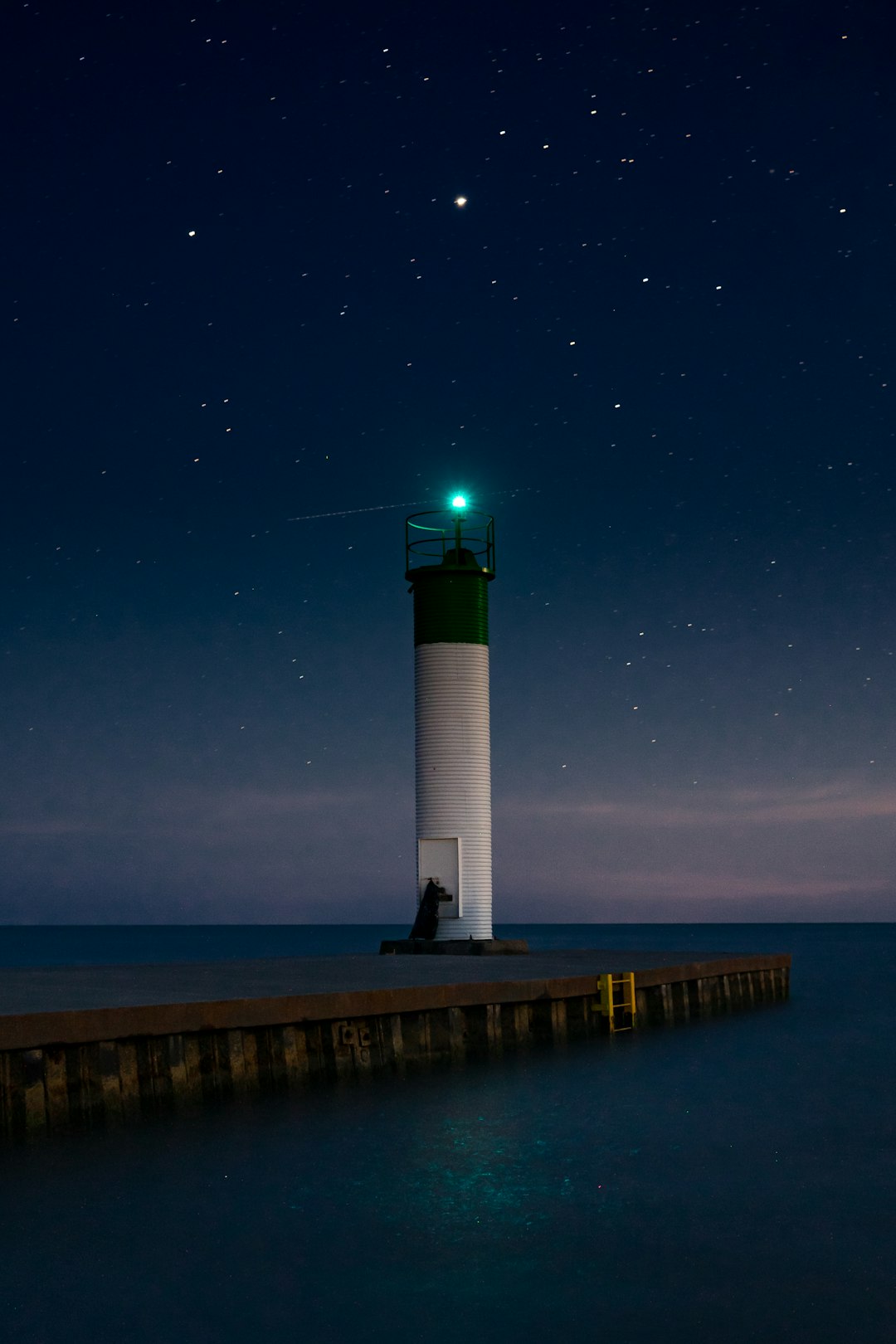 white and black lighthouse near body of water during night time