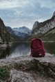 red and black backpack on rock near lake