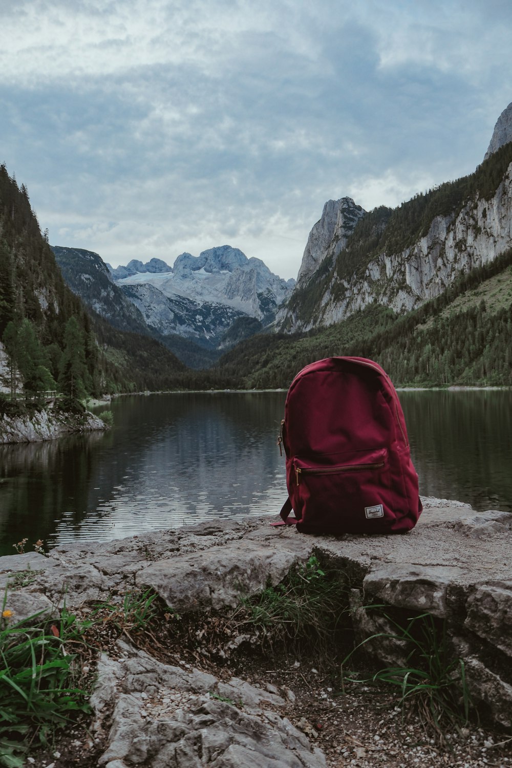 mochila vermelha e preta na rocha perto do lago