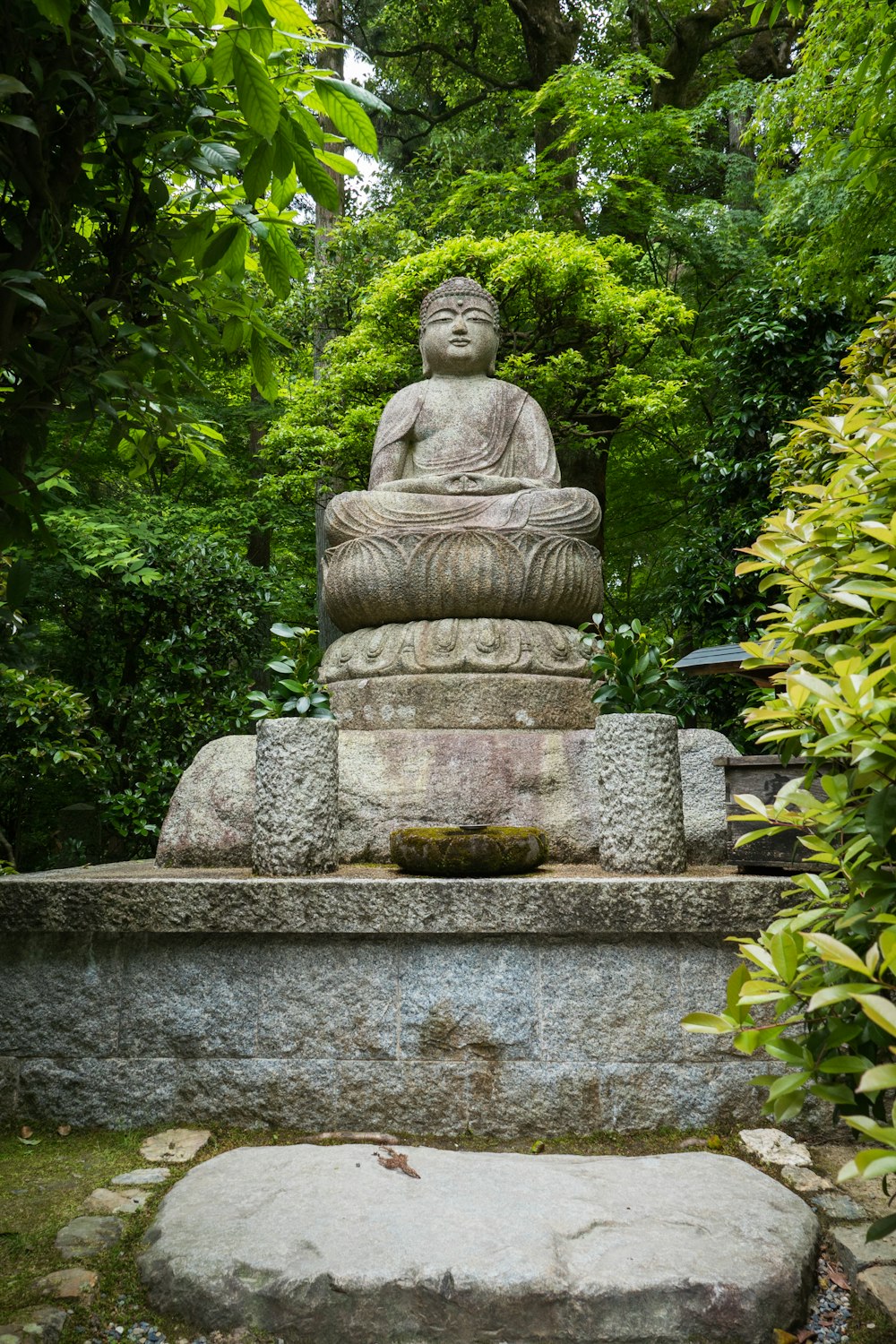 gray concrete statue near green plants during daytime