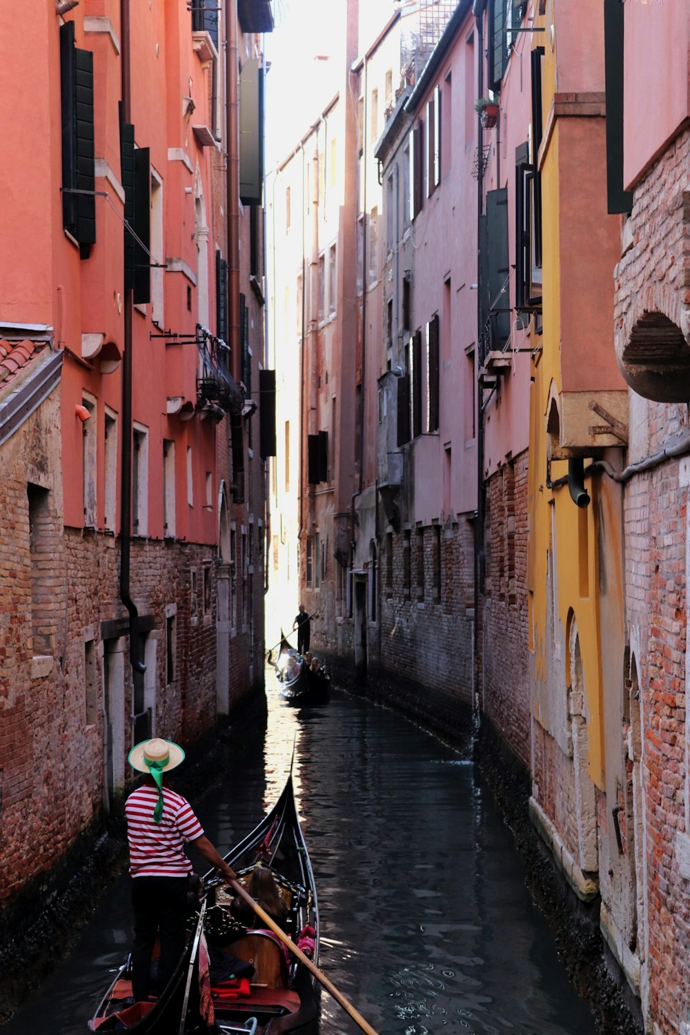 man in black and white striped shirt riding on boat on river between brown concrete buildings