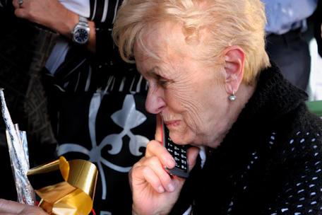 An elderly person holding a phone looking cautious while receiving a suspicious call.